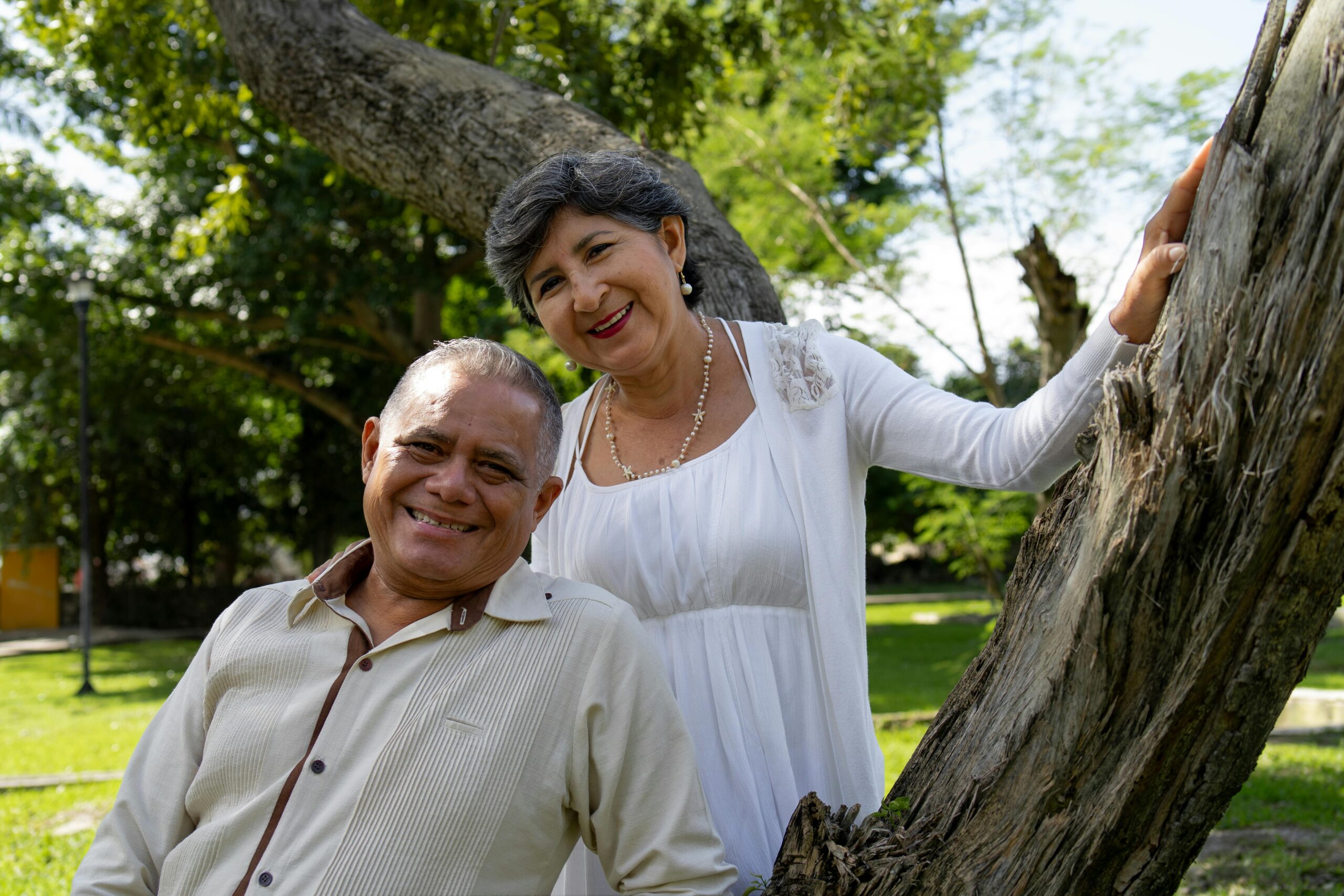 Dra. Rangel Senior couple enjoying a sunny day in a park in Merida, Yucatan, Mexico, surrounded by greenery.